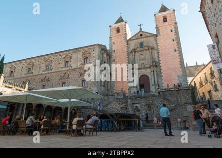 Die Kirche San Fransisco vom Platz St. George mit Touristen, die unter Sonnenschirmen sitzen. Caceres, Extremadura, Spanien. Stockfoto