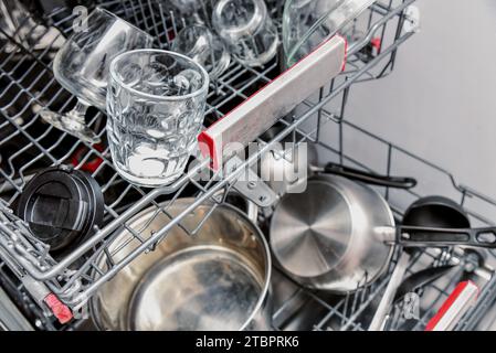 Verschiedene Küchenutensilien werden in den Geschirrspüler geladen. Geschirrspüler in der Spülmaschine. Stockfoto