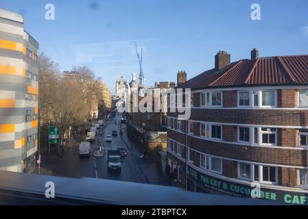 London, Großbritannien. Dezember 2023. Blick auf den Zugang zur Tower Bridge aus dem Süden, aufgenommen von einem fahrenden Vorortzug, der den Bahnhof London Bridge verlässt, mit dem Cat and Cucumber Cafe im rechten Vordergrund. Stockfoto