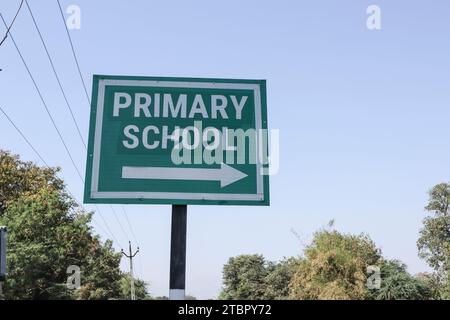 Straßenschild mit der Aufschrift Primary School (Grundschule) und Rechtspfeil. Grundschulsignalposten auf der grünen Tafel Stockfoto