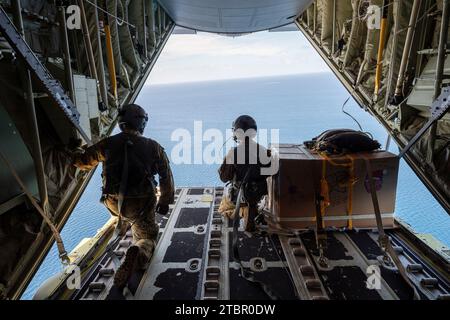 Satawan Atoll, Föderierte Staaten von Mikronesien. Dezember 2023. Joseph Snell, Senior Airman der US Air Force, links, und Staff Sgt. Matthew Muravez, 36th Expeditionary Airlift Squadron Loadmasters beobachten 130 während der Operation Christmas Drop, 5. Dezember 2023, im Satawan Atoll, Mikronesien, einen Fallschirm zu einer Lagune. Operation Christmas Drop ist die älteste humanitäre und Katastrophenhilfe-Mission, die 71.000 Pfund an Lebensmitteln, Geschenken und Hilfsgütern zur Unterstützung abgelegener Inselgemeinden im Südpazifik liefert. Quelle: Yasuo Osakabe/US Ai Stockfoto