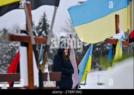 LEMBERG, UKRAINE - 6. DEZEMBER 2023 - Eine Frau steht während einer Zeremonie zum Gedenken an die Helden, die umkommen, unter den Gräbern auf dem Lytschakiw-Friedhof Stockfoto