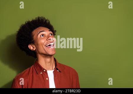 Foto von überglücklich beeindruckt Mann mit afro Haar gekleidetem braunen Hemd Blick auf erstaunliches Angebot leeren Raum isoliert auf khakifarbenem Hintergrund Stockfoto