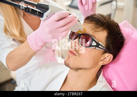 Schönheitssalon-Klient, der sich einer Laser-Gesichtshaarentfernung unterzieht Stockfoto