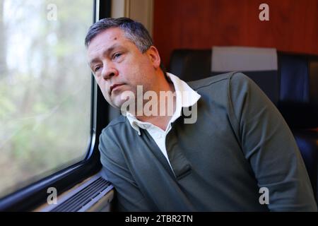 Trauriger Mann, der aus dem Fenster schaut. Stockfoto