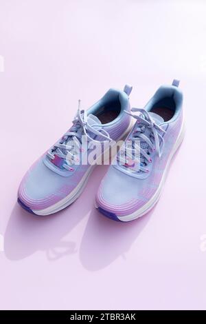 Violette blaue sportliche Laufschuhe für Frauen auf rosa Hintergrund. Mode, Trainingsschuhe für das Fitnessstudio, Schuhe für Damen. Nationalschuh Der Welttag Stockfoto