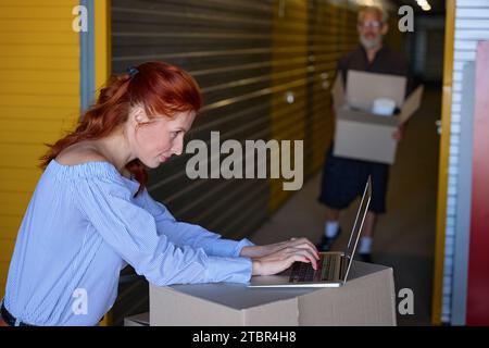 Pretty Lady benutzt einen Laptop in einem Lagerhaus Stockfoto