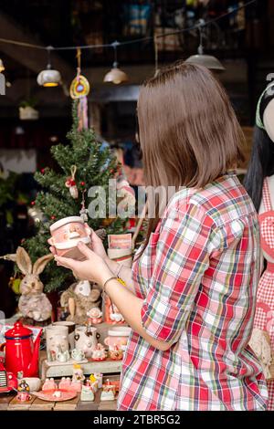 Frau, die Weihnachtsgeschenke in einem kleinen handwerklichen Töpferladen auswählt. Winterferien Stimmung im tropischen Klima. Stockfoto