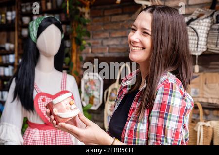 Frau, die Weihnachtsgeschenke in einem kleinen handwerklichen Töpferladen auswählt. Winterferien Stimmung im tropischen Klima. Stockfoto