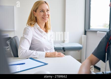 Fröhliche Patientin im Gespräch mit dem Arzt in der Primärberatung Stockfoto