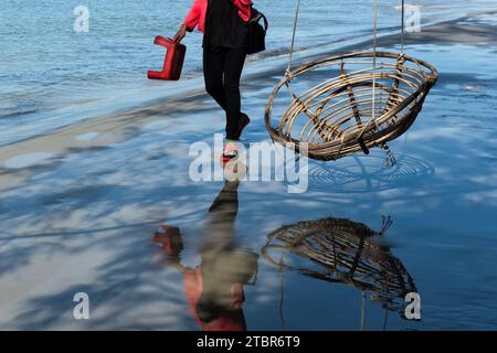 Frau, die an einem Schaukelstuhl am Strand in Kambodscha vorbeigeht Stockfoto