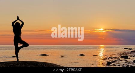 Frau, die Yoga bei Sonnenuntergang am Strand feiert Stockfoto