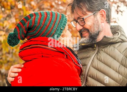 Erwachsene Menschen, die sich in Freizeitaktivitäten im Freien treffen. Eine Frau umarmt den Mann mit Liebe. Beziehung und romantischer Ort. Herbst Natur Hintergrund. Winterbekleidung für den Lebensstil. Romantik. Verklebung. Stockfoto