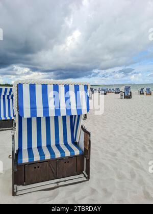 Deutschland, Mecklenburg-Vorpommern, Prerow, Wolkenbildung am Strand an der Ostseeküste, Gewitteratmosphäre, Regenwolke über Liegestuhl im Vordergrund Stockfoto