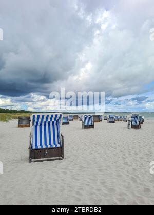 Deutschland, Mecklenburg-Vorpommern, Prerow, Wolkenbildung am Strand an der Ostseeküste, Gewitteratmosphäre, Regenwolke über Liegestuhl im Vordergrund Stockfoto