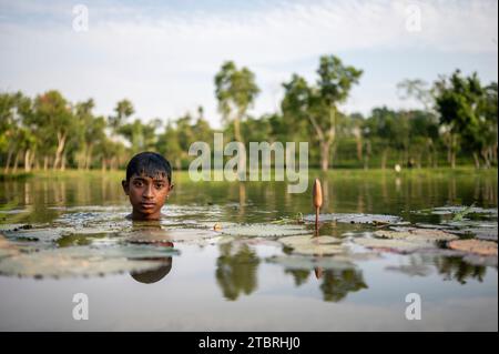 Ein Teenager, der ein Bad in einem Teich auf den Teeplantagen von Sylhet nimmt. Bangladesch. Stockfoto