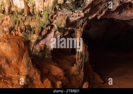 Mehrfarbige Steinsäulen in der Quadiriki-Höhle im Arikok-Nationalpark, Aruba. Farbige Steinwände und -Decke; offene Höhle im Hintergrund. Stockfoto