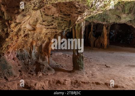 Mehrfarbige Steinsäulen in der Quadiriki-Höhle im Arikok-Nationalpark, Aruba. Farbige Steinwände und -Decke; offene Höhle im Hintergrund. Stockfoto