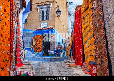 Geschäfte mit farbenfrohen Berberteppichen / marokkanischen Teppichen in der Gasse der Medina / historische Altstadt der Stadt Chefchaouen / Chaouen, Marokko Stockfoto