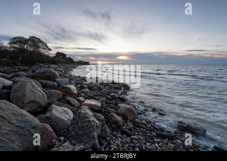 Sonnenaufgang am Strand Hovmarken auf der dänischen Insel Mön in der Ostsee, Steine am Strand, Mole, groyne, Mön, Dänemark Stockfoto