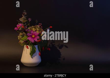 Blumenvase mit bunten Herbstblumen auf schwarzem Hintergrund Stockfoto