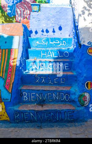 Chefchaouen, Marokko. Oktober 2022 - gemalte und dekorierte Treppen, mit Begrüßungsworten in einigen Sprachen auf den Stufen, die Zugang zu einem Haus ermöglichen Stockfoto