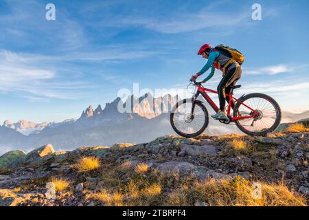 Italien, Venetien, Provinz Belluno, Falcade, Outdoor-Aktivitäten mit der Familie, Radfahrerin mit E-Bike in den Bergen, im Hintergrund die Pale di San Martino Kette bei Sonnenuntergang Stockfoto