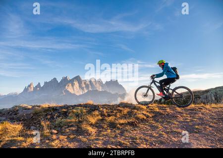 Italien, Venetien, Provinz Belluno, Falcade, Outdoor-Aktivitäten mit der Familie, junge Radfahrer, die mit dem E-Bike in den Bergen fahren, im Hintergrund die Pale di San Martino Kette bei Sonnenuntergang Stockfoto