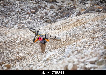 Italien, Dolomiten, Bergsteiger auf einem alpinen Trail mit dem Mountainbike auf dem Rücken in einem sehr schwierigen Abschnitt Stockfoto