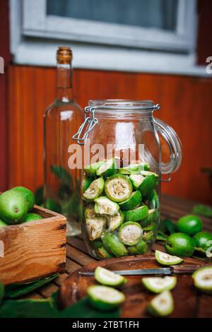 Hausgemachten Walnusslikör herstellen. Unreife Nüsse im Glas und Alkohol in der Flasche auf dem Tisch Stockfoto