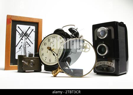 Vintage-Kameras, zerlegter Wecker und Vergrößerungsglas auf weißem Hintergrund Stockfoto