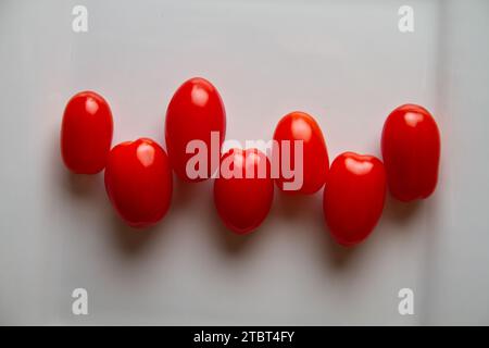 Lebhafte Reihe frischer roter Traubentomaten auf weißem Hintergrund Stockfoto