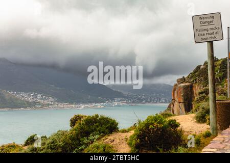 Hout Bay, eine Fischerstadt auf der Kap-Halbinsel südlich von Kapstadt, Südafrika, ist vom Chapman's Peak aus unter stürmischem Frühlingshimmel zu sehen Stockfoto