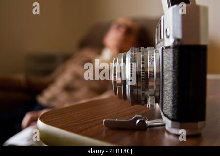 Vintage 35 mm Filmkamera auf Holzoberfläche mit verschwommenem Alter Mann im Hintergrund Stockfoto