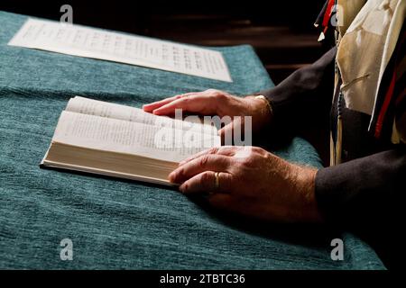 Ältere Hände lesen zeremonielles Buch mit Notenhintergrund Stockfoto