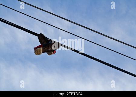 Urban Nostalgia – Schuhe, die auf der Power Line gegen den Himmel hängen Stockfoto