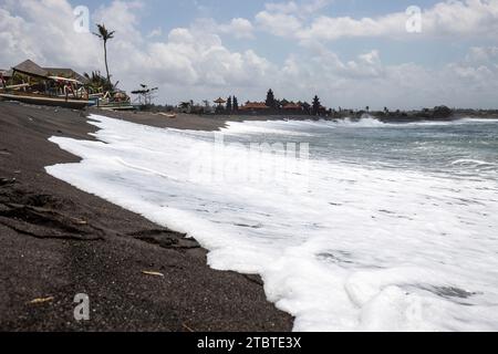 Traditionelles Fischerboot Jukung, an einem schwarzen Sandstrand direkt am Meer, abendliche Landschaft am Meer auf der tropischen Insel Sanur, Bali, Indonesien Stockfoto