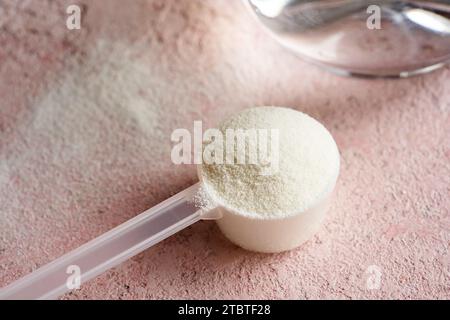 Kollagenpulver in einem Plastik-Messlöffel auf rosa Hintergrund Stockfoto