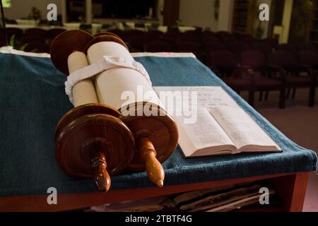 Tora-Rolle auf blauem Tuch mit leeren Synagogenstühlen im Hintergrund Stockfoto