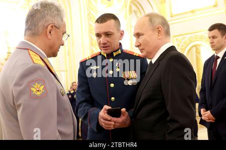 Moskau, Russland. Dezember 2023. Der russische Präsident Wladimir Putin, rechts, und Verteidigungsminister Sergej Shoigu, links, hören auf Junior Sergeant Nikolai Kharchenko nach einer Zeremonie, bei der Goldsterne-Medaillen am Vorabend des Helden des Vaterlandes-Tages in St. Georgshalle des Großen Kreml-Palastes, 8. Dezember 2023 in Moskau, Russland. Quelle: Mikhail Klimentyev/Kreml Pool/Alamy Live News Stockfoto