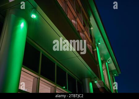 Grün beleuchtetes modernes Gebäude in nächtlicher Stadtlandschaft Stockfoto