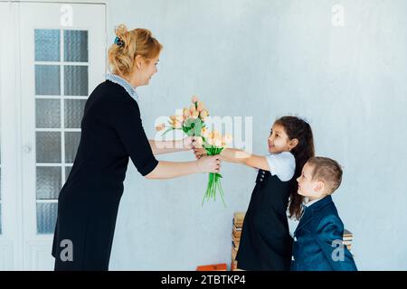 Schulkinder schenken dem Lehrer Blumen für den Urlaub im Klassenzimmer Stockfoto