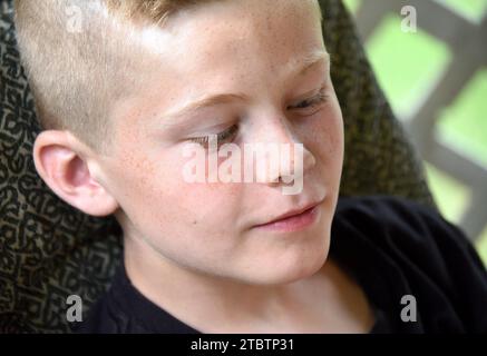 Nahaufnahme des Jungen zeigt ihn in Gedanken verloren. Er schaut nicht in die Kamera. Sommersprossen streuen sein Gesicht. Stockfoto