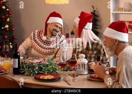 Junger Mann, der abends mit seiner Familie zu Hause weihnachtlich zu Abend isst Stockfoto