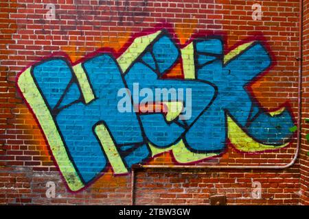 Lebendige HSK-Graffiti-Kunst auf verwitterter Ziegelmauer in Urban Illinois Stockfoto