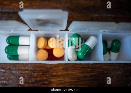 Pillen-Organizer-Box, mit orangefarbenen und grünen Pillen Stockfoto