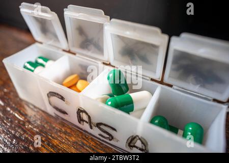 Pillen-Organizer-Box, mit orangefarbenen und grünen Pillen Stockfoto