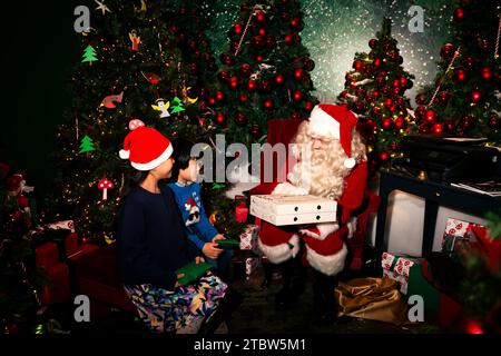 Weihnachtsmann schenkt Kindern zu Weihnachten Geschenke. Stockfoto