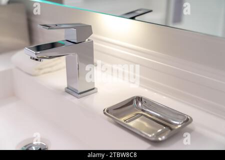 Modernes weißes Waschbecken und silberner Wasserhahn mit einer Seifenschale aus Metall im Hotelbad Stockfoto