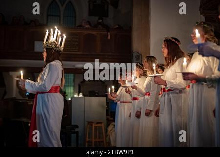 London, Großbritannien. Dezember 2023. Sankta-Lucia-Feiern des schwedischen Chors Norrsång East London in der St. Mary’s Church in Walthamstow. Isabelle Wasmuth Dunnett trägt eine Kerzenkrone, die die hl. Lucy symbolisiert, während sie die Sankta Lucia feiert, basierend auf der Tapferkeit und dem Martyrium eines jungen sizilianischen Mädchens St. Lucy (Lucia von Syrakus 283–304). Guy Corbishley/Alamy Live News Stockfoto